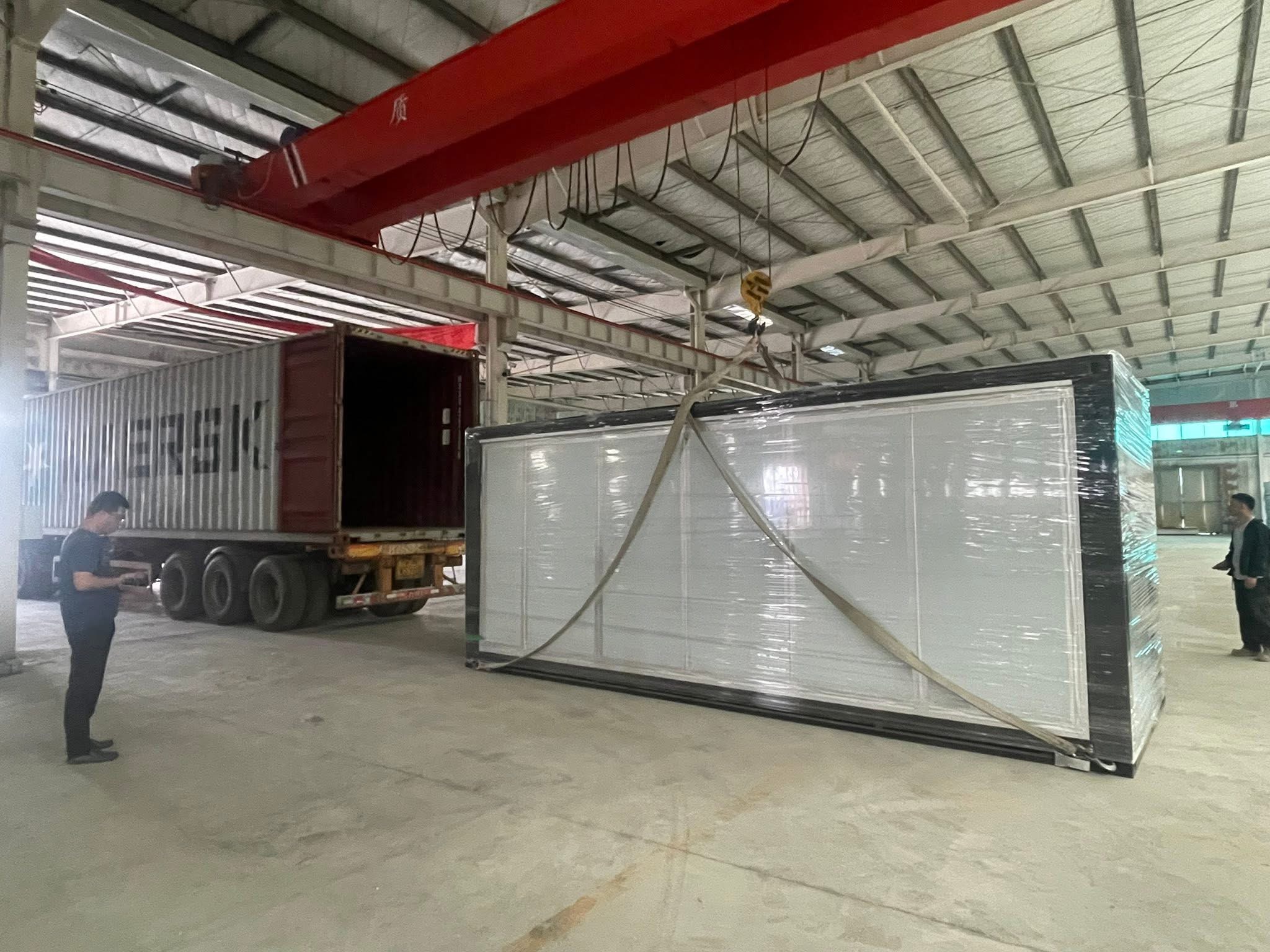 Wrapped outdoor kitchen module being prepared for loading with crane support