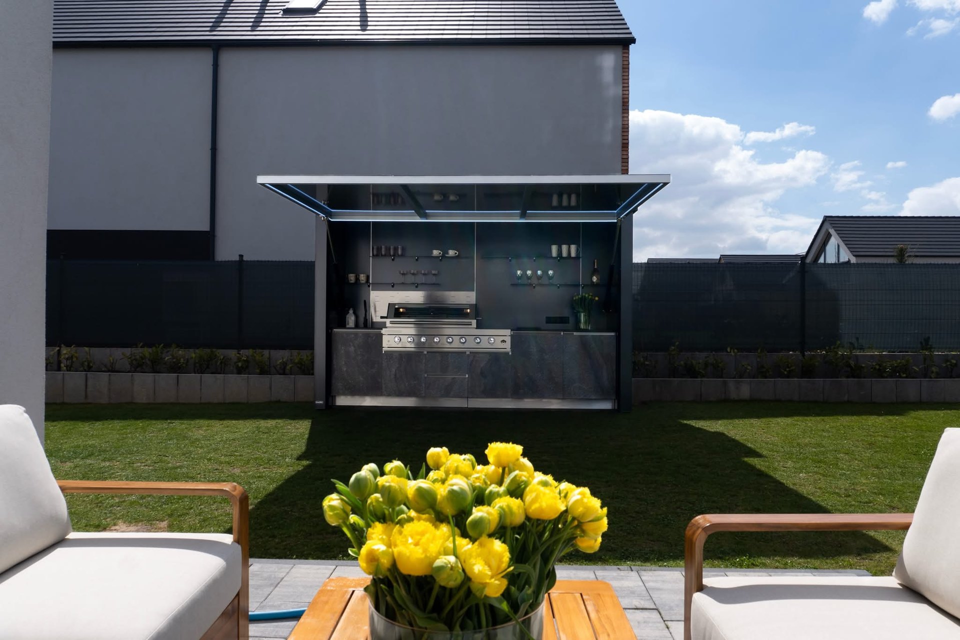 Modular outdoor kitchen with fold-down canopy open in a garden
